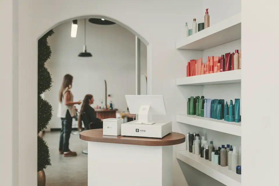 Recepção de salão com passagem em arco e prateleiras de produtos capilares