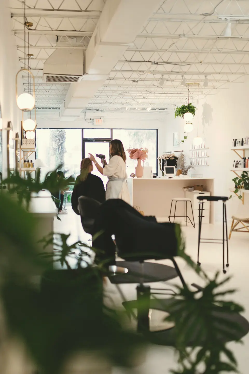 Ambiente claro de salão de beleza com plantas e profissionais atendendo