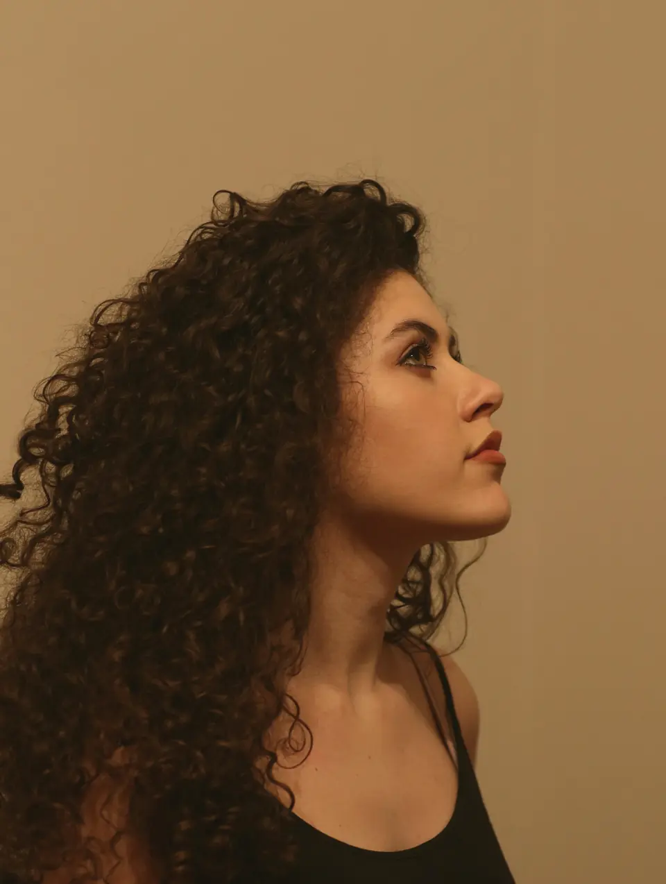 Mulher de perfil com cabelos cacheados volumosos e definidos