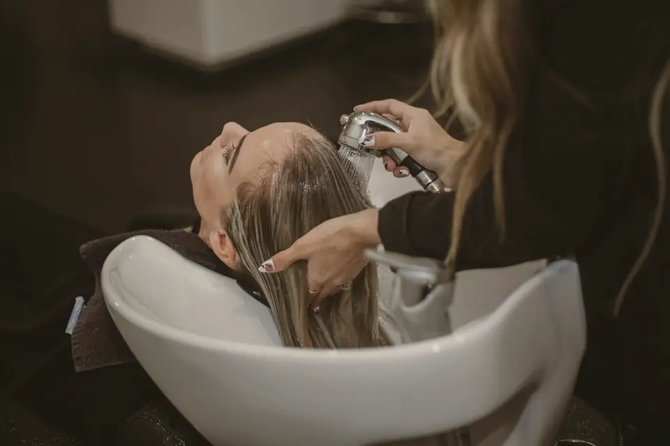 Cliente relaxando no lavatório enquanto a profissional lava seus cabelos
